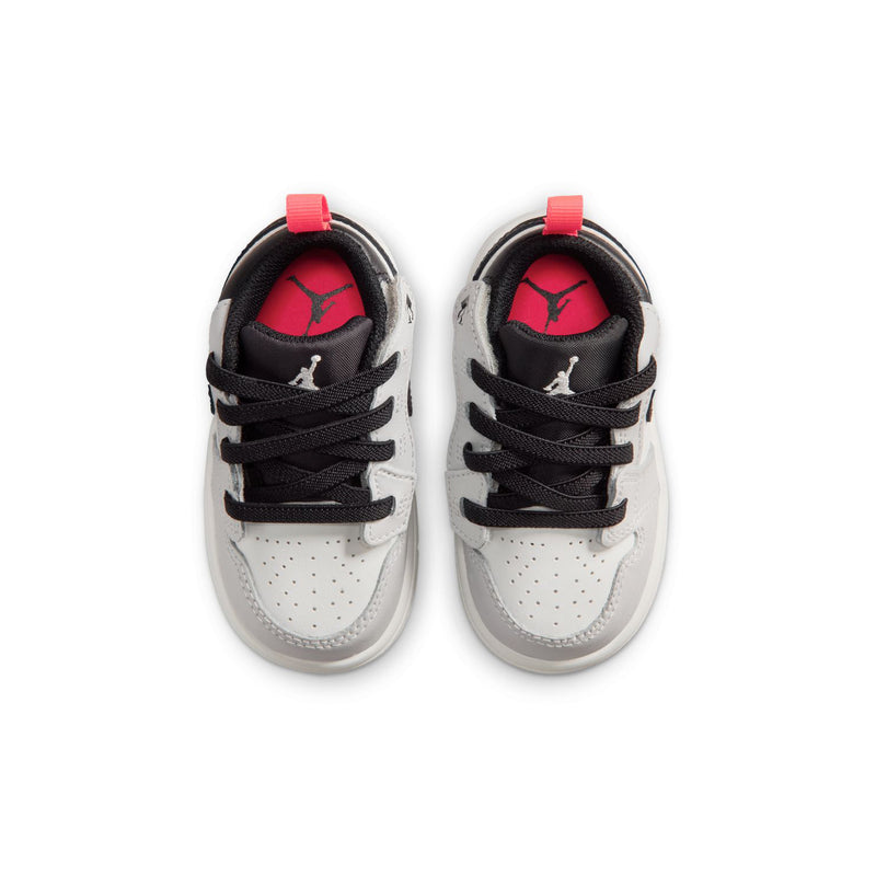 Kids low-top sneakers showing red inner lining and black lace-up with white panels