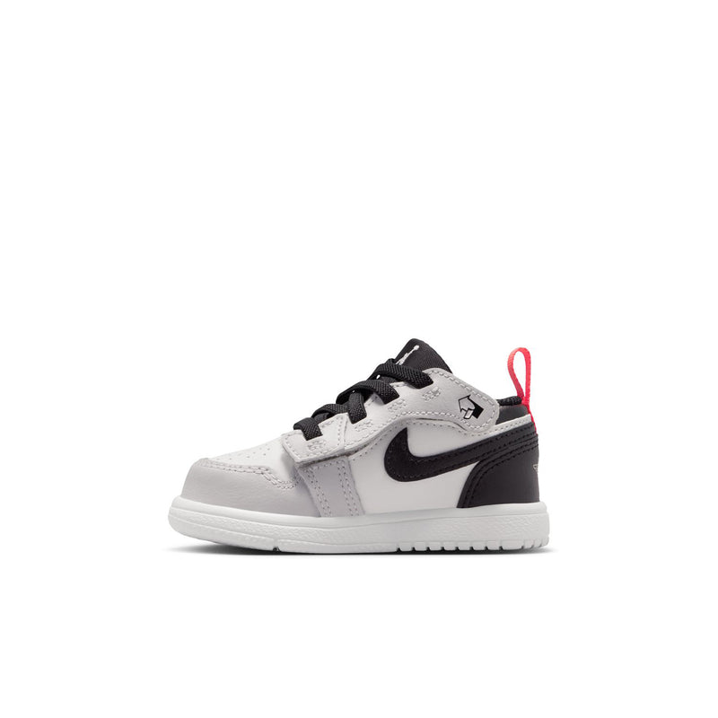 Kids low-top sneakers in white and black with black swoosh and red lace pull loop