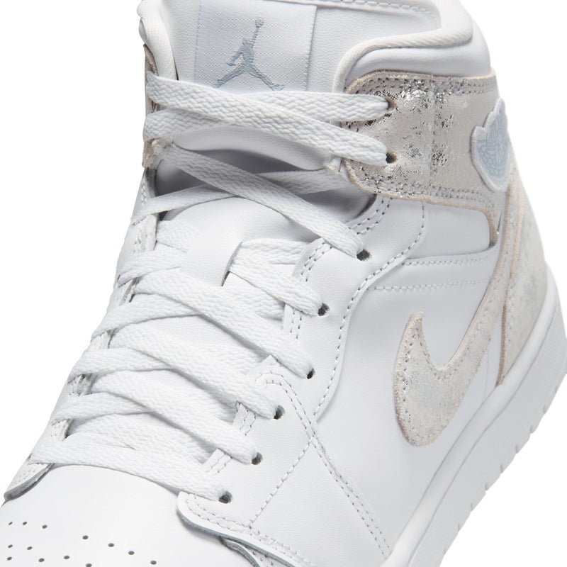 Close-up of men's mid-top sneakers: white laces, swoosh, and speckled collar panel