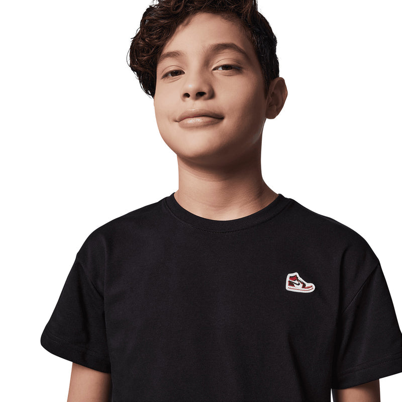 Black youth crewneck t-shirt close-up with sneaker logo patch on left chest
