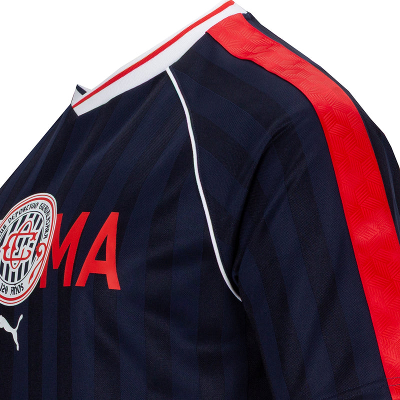 Navy jersey shoulder detail with red stripe panel, piping, and crest logo