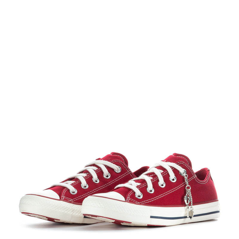 Womens red low-top canvas sneakers with heart-shaped dangling charms and white laces