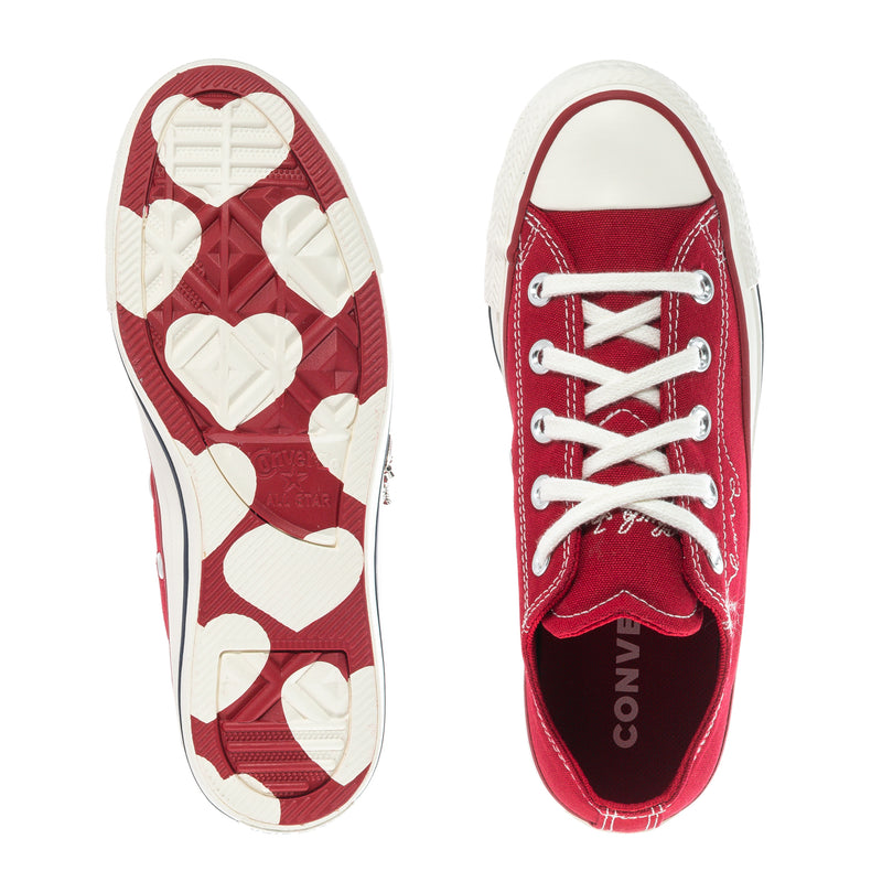Pair of red low-top sneakers showing heart-patterned outsole and white rubber sole