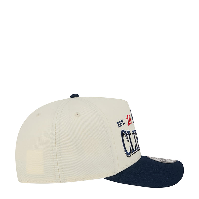 Two-tone A-frame cap with cream crown, navy curved brim, side team crest