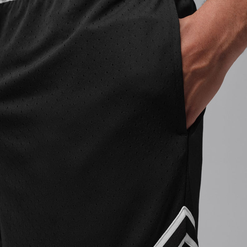 Black basketball shorts fabric close-up with subtle perforation and white trim