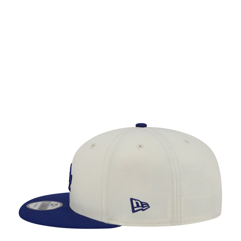 Two-tone baseball cap with cream crown and royal blue brim, featuring New Era logo.