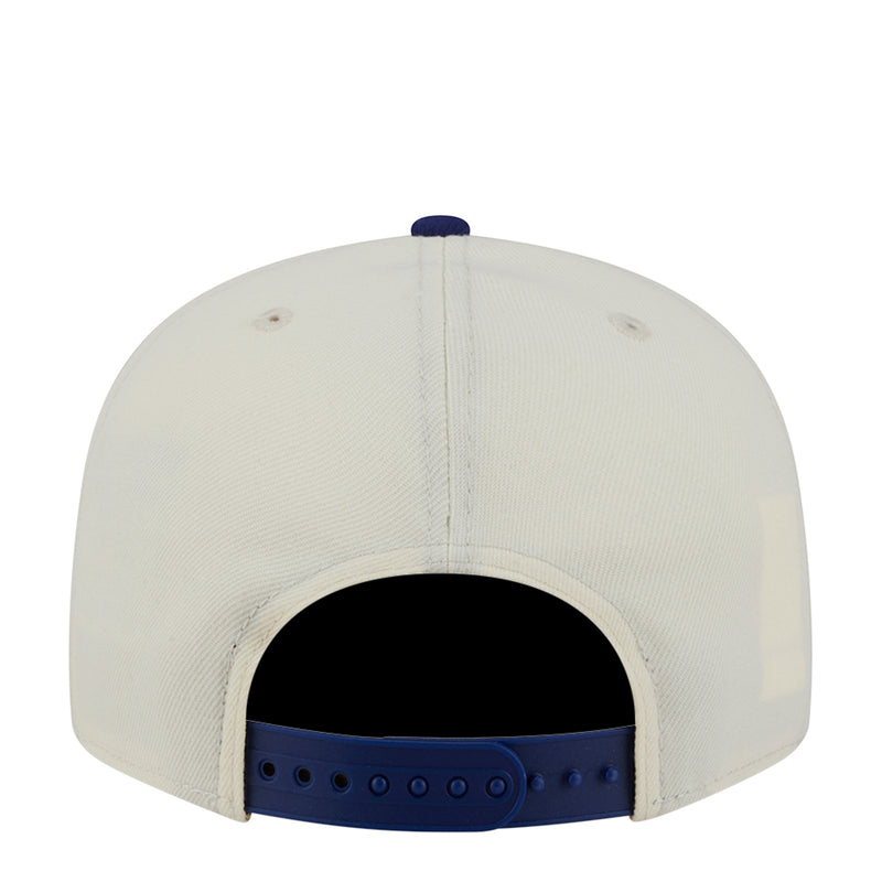 Two-tone baseball cap with cream crown and royal blue adjustable back strap.