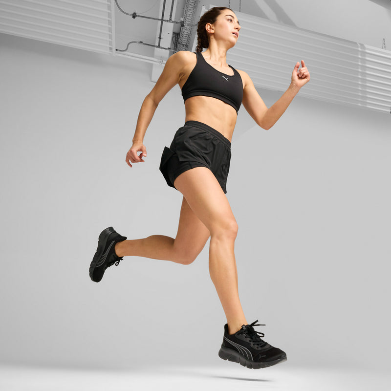 Black lace-up running shoes worn during stride, with cushioned textured sole.