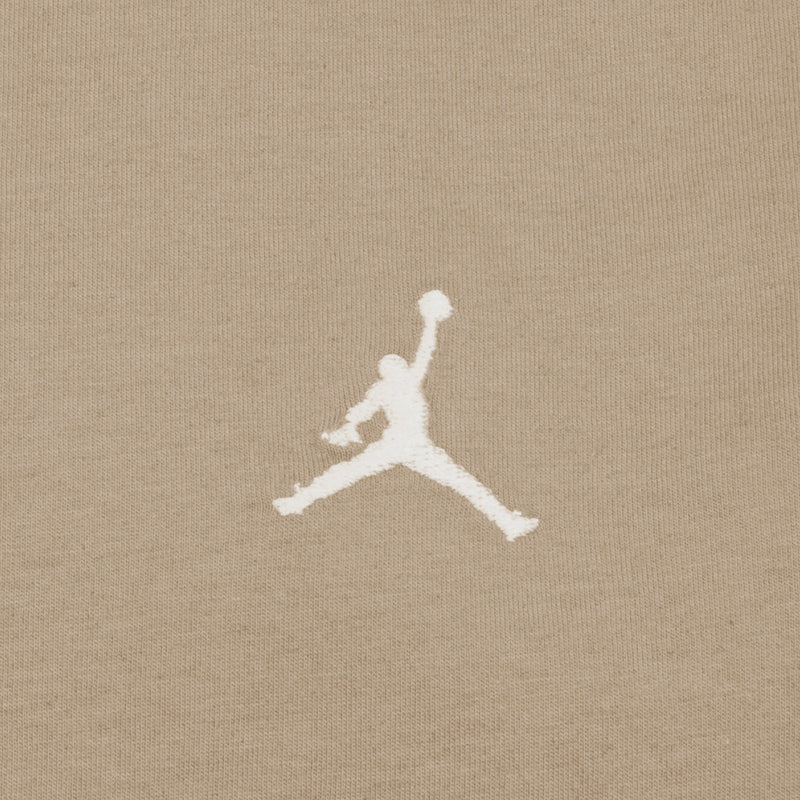 Close-up of white Jumpman logo embroidery on hemp beige youth tee fabric