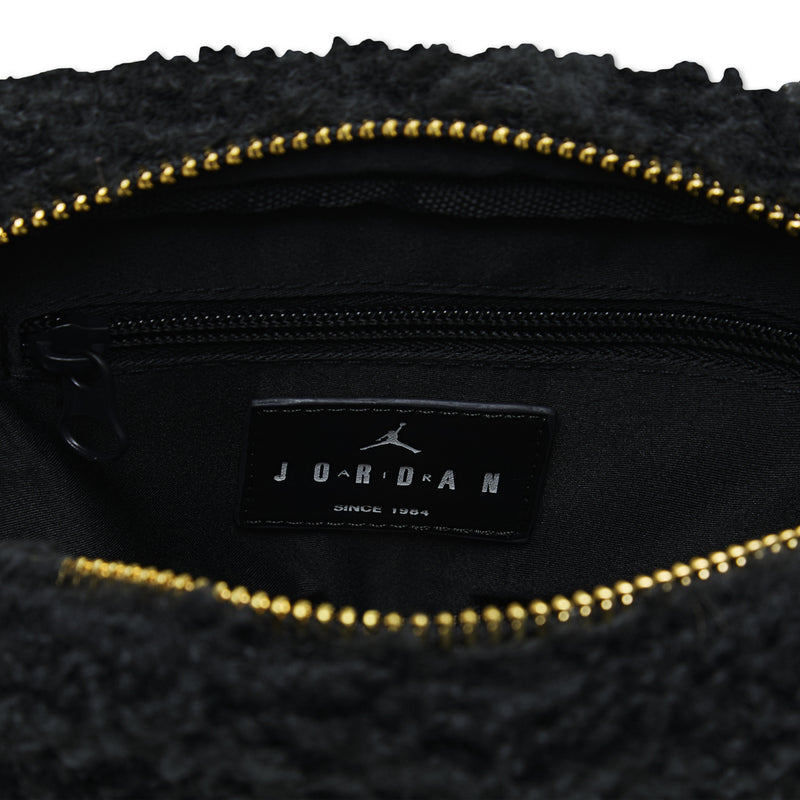 Black interior pocket with leather brand label and gold zipper on sherpa camera bag