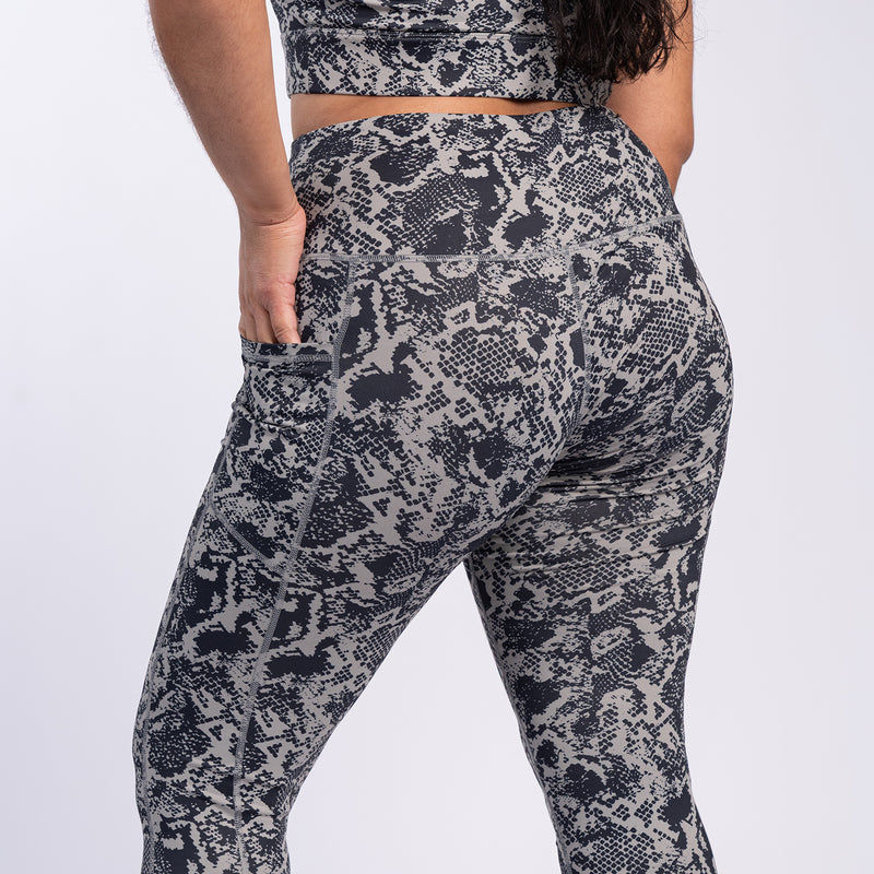 Back view of snake print high-waist leggings in dark gray and black