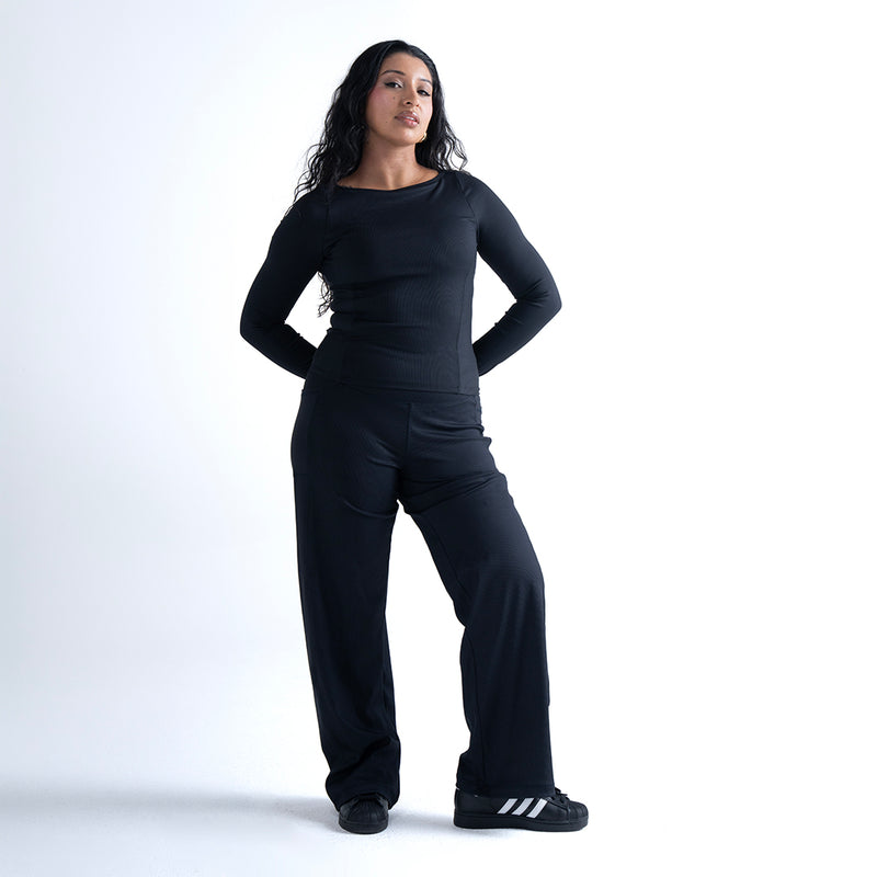 Black wide-leg pants with high-rise elastic waistband, worn by model.