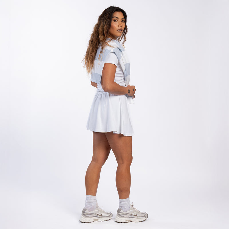 White mini skirt with elastic waistband, front tie, and softly pleated flared shape