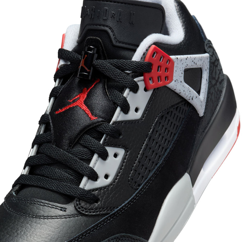 Close-up of men's black low-top sneakers with red lace accents and white panels