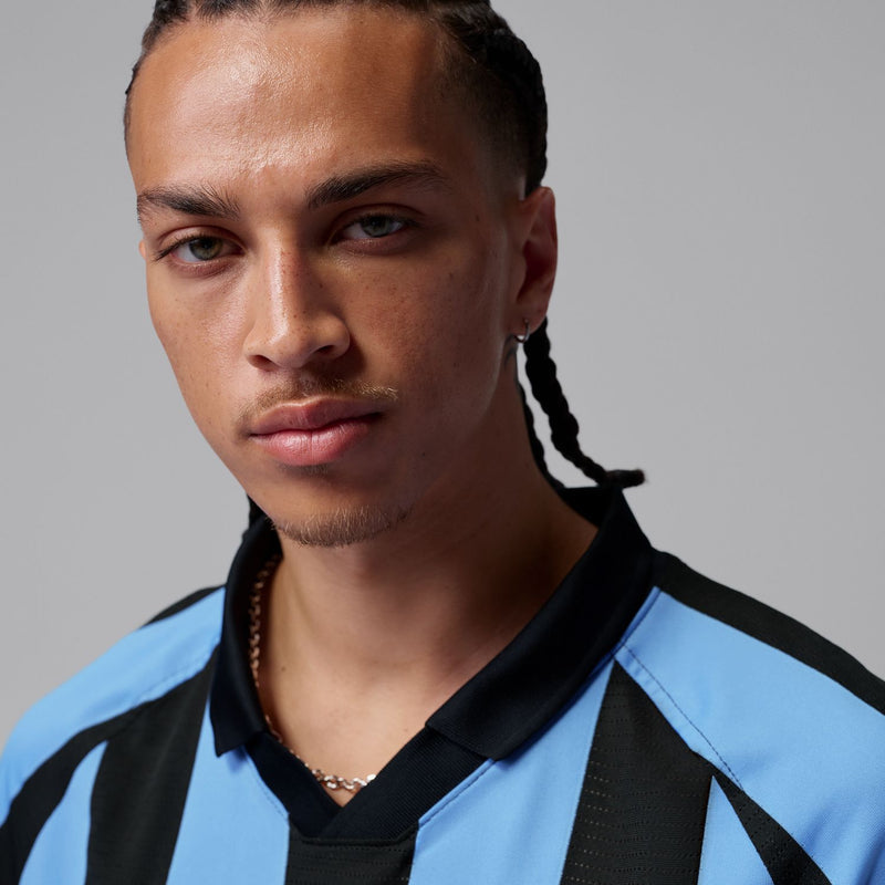 Men's jersey collar close-up with black trim and blue-and-black stripe panel