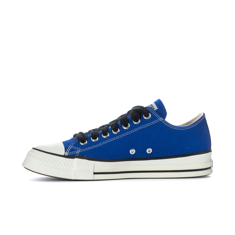 Blue low-top canvas sneaker side profile with black laces, metal eyelets, white sole