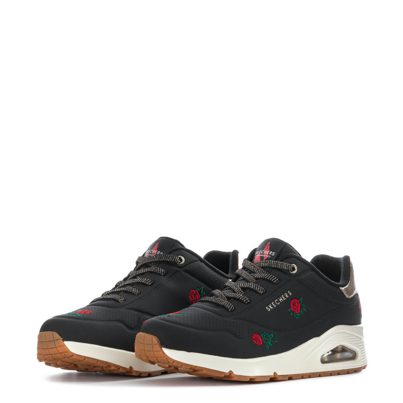 Pair of black low-top sneakers with white soles, rose embroidery and tan rubber outsole