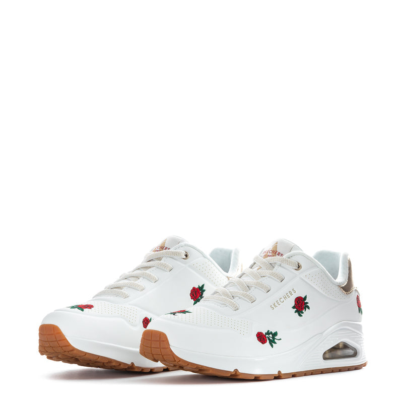 Pair of white women's sneakers with red rose graphics, gum outsole, metallic heel window